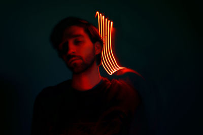 Close-up of young man with illuminated lights against wall