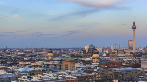 Aerial view of cityscape against cloudy sky