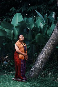 Smiling woman wearing traditional clothing while standing against trees