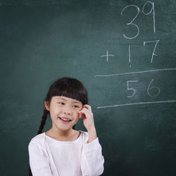 Girl smiling while learning mathematics on blackboard