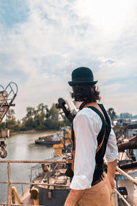 Rear view of man standing on boat against sky