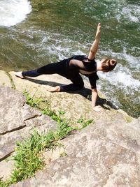 Full length portrait of woman with arms raised on rock