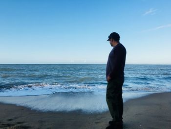 Rear view of man standing at cairns australia beach against sky