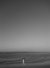 Woman standing on beach against clear sky