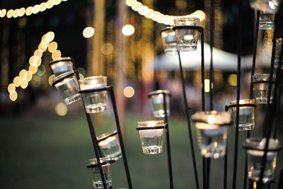 Close-up candle in small glass jars in the steel holder with blurred bokeh lights background