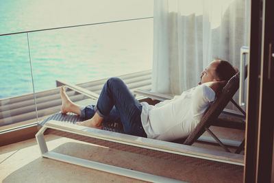 Side view of woman resting on window