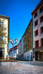 Street by buildings against clear blue sky