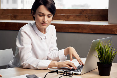 Woman using laptop while working at office