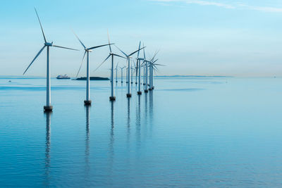Windmills on sea against sky 