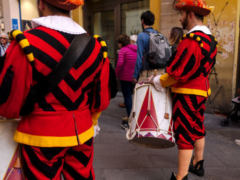 Rear view of people walking on street in city