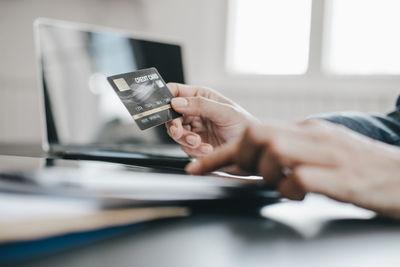 Midsection of man using laptop on table