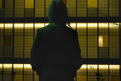 Rear view of woman standing against illuminated ceiling