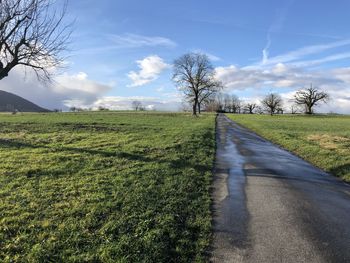 Road amidst field against sky