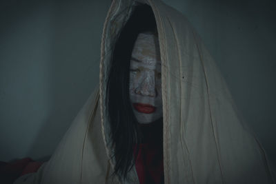 Close-up of woman with spooky make-up wrapped in blanket