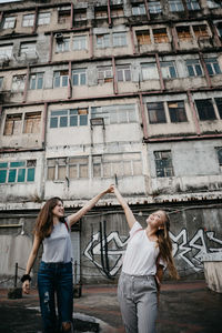 Smiling friends standing against building in city