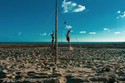 People playing beach volleyball against sky