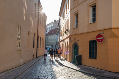 Rear view of people walking on street amidst buildings in city