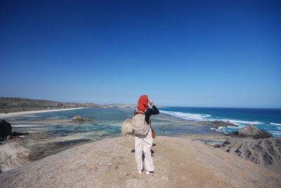 Rear view of man on beach against clear sky