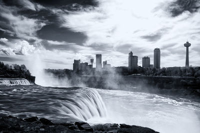 View of waterfall in city against sky