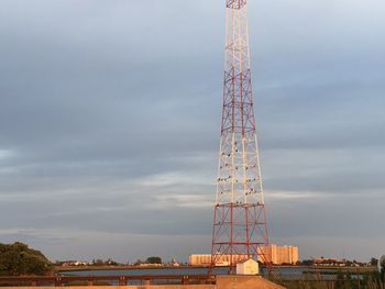 Low angle view of communications tower against cloudy sky