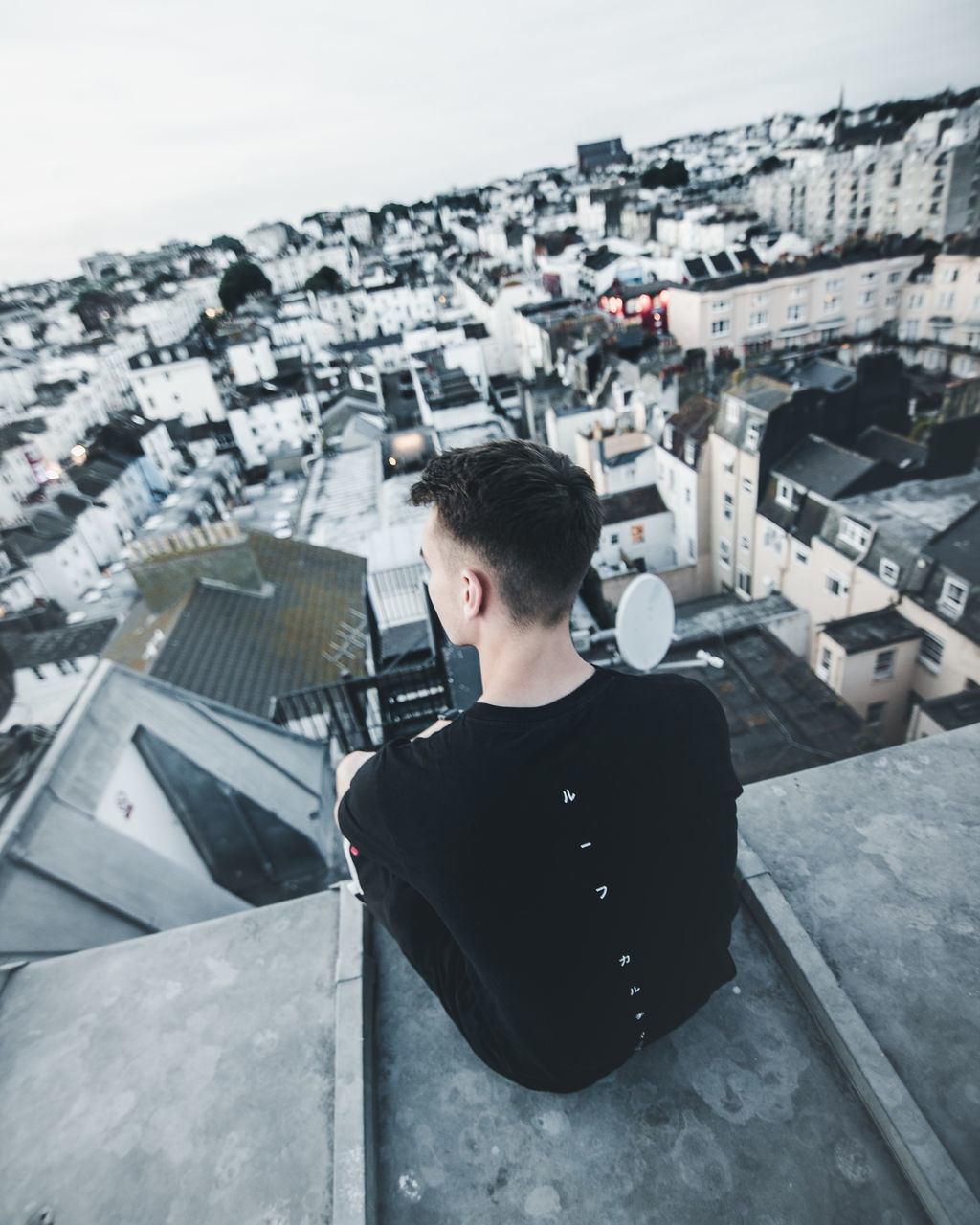 YOUNG MAN WITH CITYSCAPE IN BACKGROUND AGAINST SKY