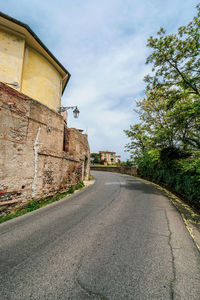 Empty road amidst buildings against sky