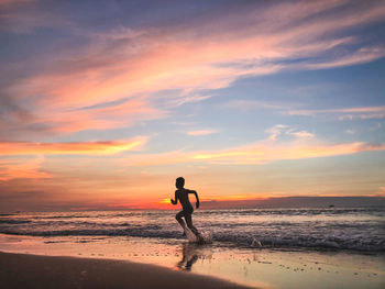 Man on beach against sky during sunset