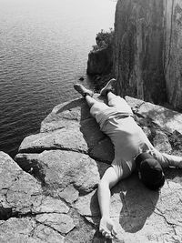 Man lying on cliff against sea