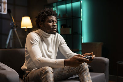 Portrait of young man sitting on sofa at home