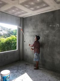 Full length side view of man standing against wall