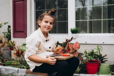 Smiling girl cutting veggie on wood board