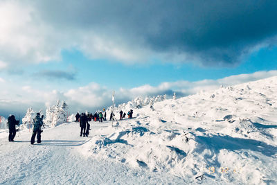 People on snow covered mountain against sky