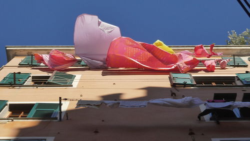 Low angle view of buildings against clear sky with drying laundry