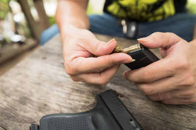 Midsection of man holding handgun at wooden table in balcony