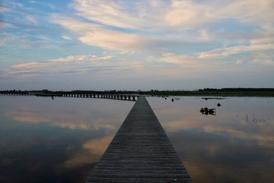 Pier over lake against sky during sunset