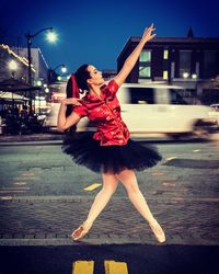 Full length of ballet dancer dancing on street at night