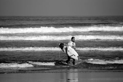 Boy standing on beach against clear sky