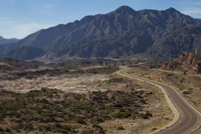 Scenic view of road by mountains against sky