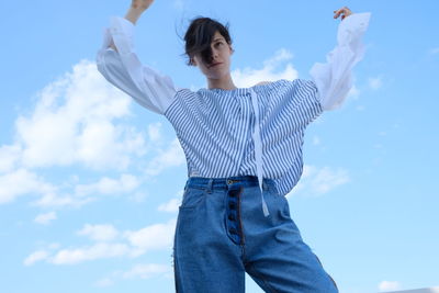 Low angle view of woman standing against blue sky