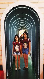 Full length portrait of smiling woman standing against wall