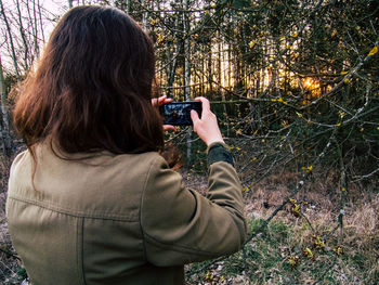 Rear view of woman photographing with smart phone