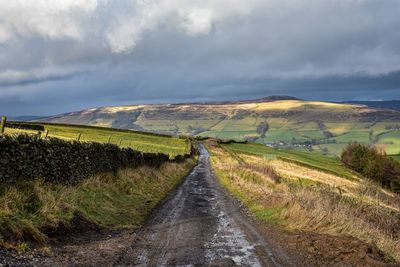 Road amidst field against sky