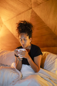 Portrait of young woman sitting on bed at home