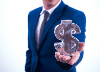 Midsection of man holding camera while standing against white background