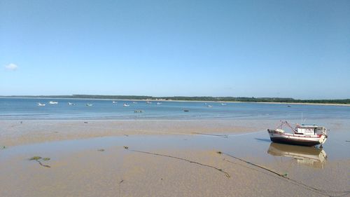 Boat moored on beach against sky