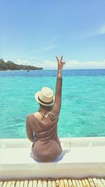 Rear view of woman wearing hat against sea