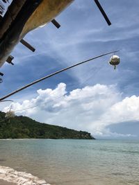 Low angle view of hanging over sea against sky