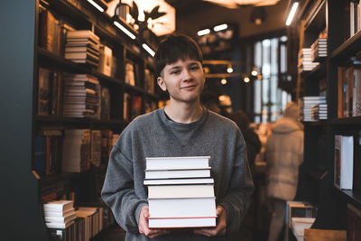 Portrait of young holding books in library