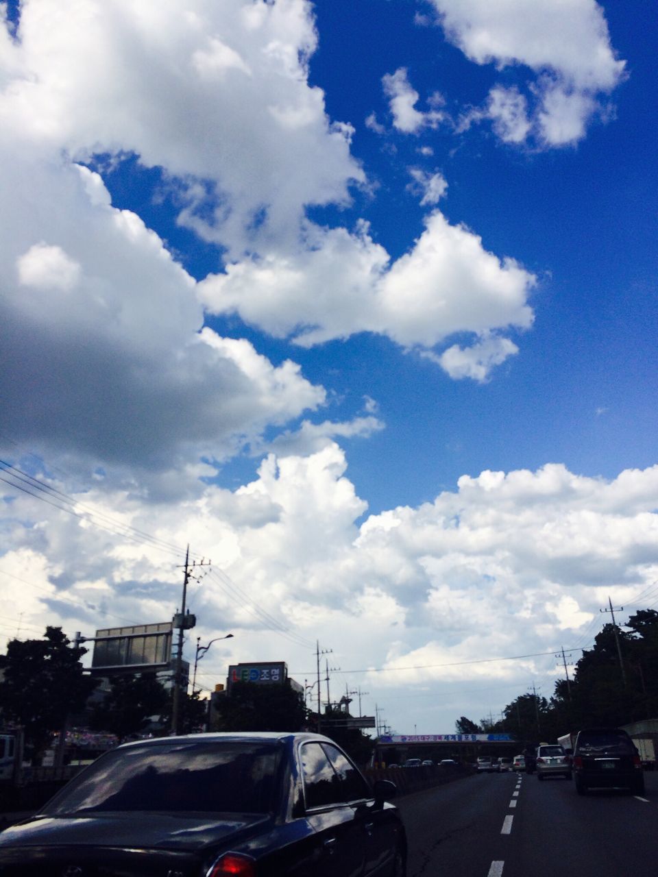 transportation, car, land vehicle, mode of transport, sky, road, cloud - sky, street, cloud, the way forward, on the move, road marking, blue, cloudy, travel, diminishing perspective, vanishing point, highway, day, outdoors