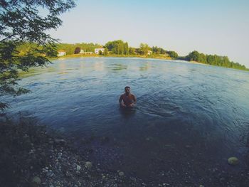 Man swimming in lake against clear sky